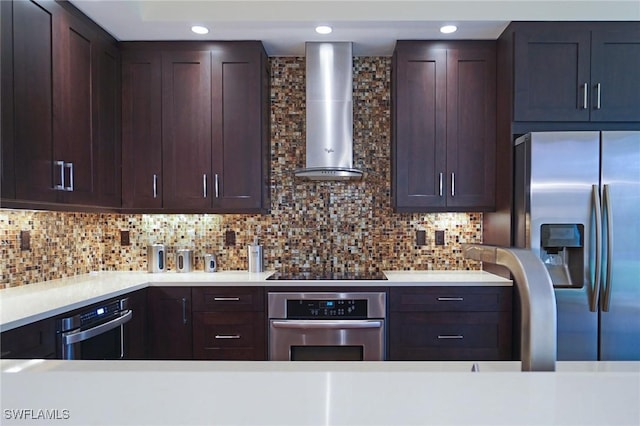 kitchen with backsplash, appliances with stainless steel finishes, wall chimney exhaust hood, and dark brown cabinetry