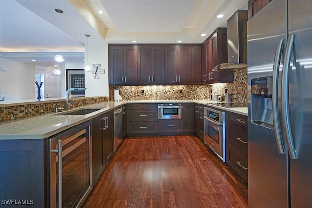 kitchen featuring kitchen peninsula, stainless steel appliances, beverage cooler, wall chimney exhaust hood, and sink