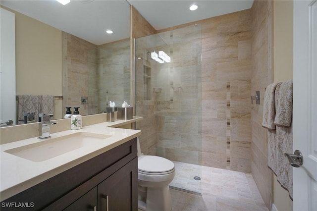 bathroom with toilet, tiled shower, and vanity