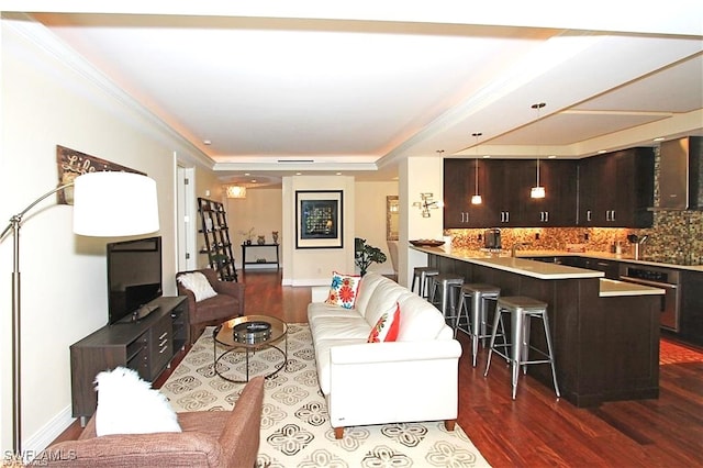 living room featuring dark hardwood / wood-style flooring, a tray ceiling, and ornamental molding