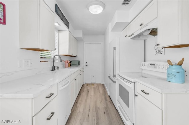 kitchen featuring sink, white appliances, light stone countertops, light hardwood / wood-style floors, and white cabinets