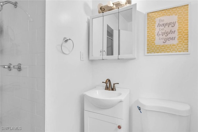 bathroom featuring vanity, tiled shower, and toilet