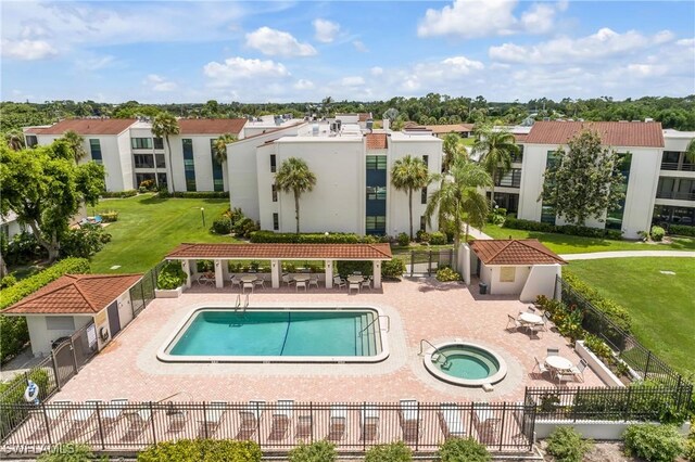 rear view of house featuring a patio area, a lawn, and a swimming pool with hot tub