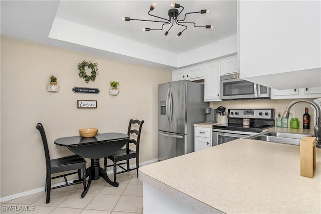 kitchen featuring sink, white cabinetry, a chandelier, light tile patterned floors, and appliances with stainless steel finishes