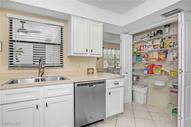 kitchen with sink, light tile patterned floors, white cabinets, and dishwasher