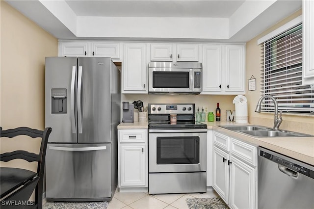 kitchen with stainless steel appliances, white cabinetry, sink, and light tile patterned flooring