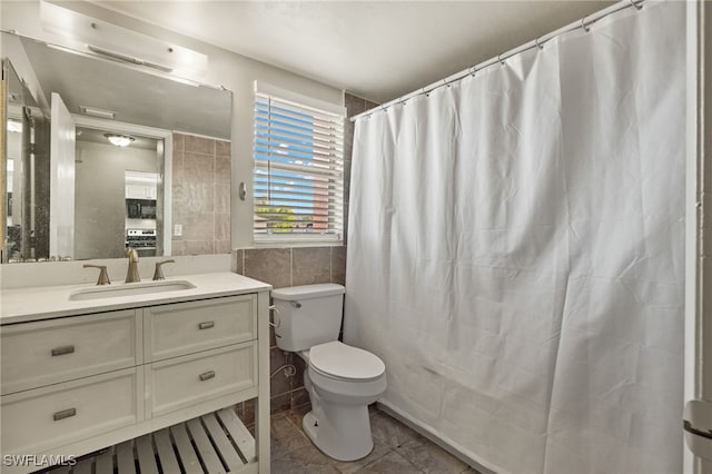 bathroom with vanity, tile walls, toilet, and tile patterned flooring