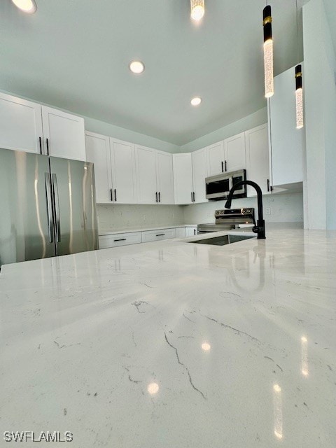 kitchen with white cabinets, sink, pendant lighting, and appliances with stainless steel finishes