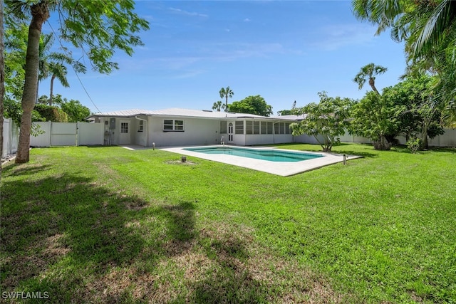 rear view of house featuring a fenced in pool and a lawn