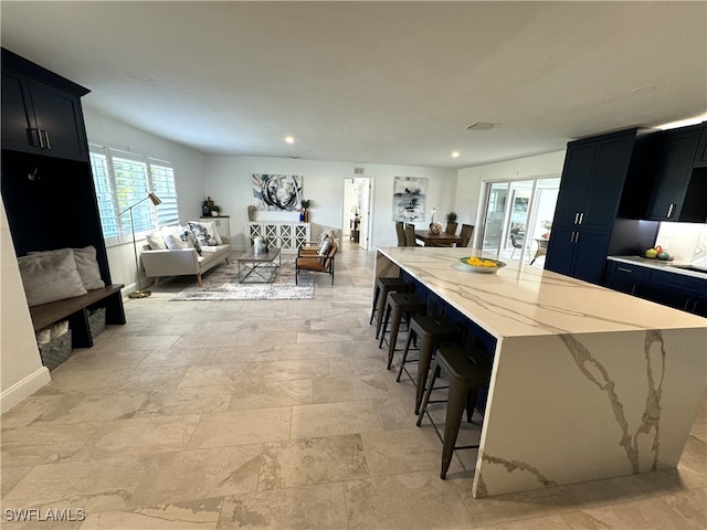 kitchen with light stone counters, a breakfast bar area, and a center island