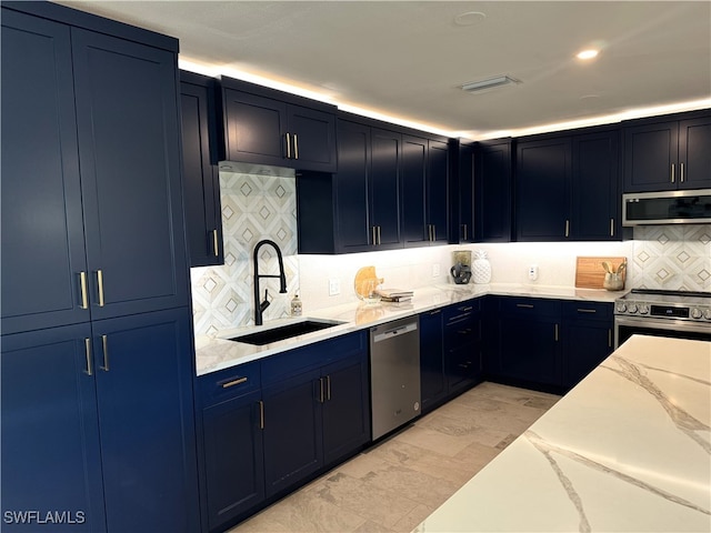 kitchen with stainless steel appliances, sink, tasteful backsplash, light stone countertops, and blue cabinets