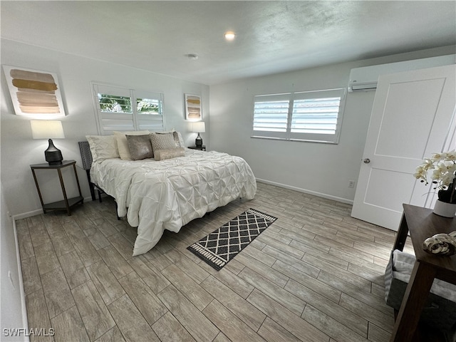 bedroom with an AC wall unit and light hardwood / wood-style flooring