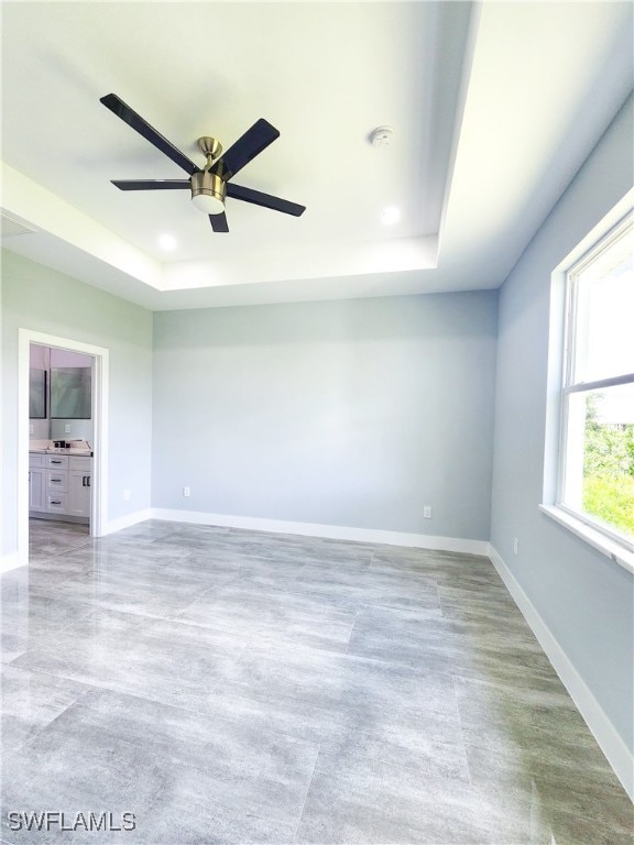 spare room with ceiling fan and a raised ceiling