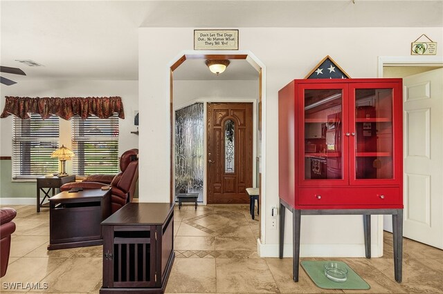 foyer entrance featuring visible vents, arched walkways, and baseboards