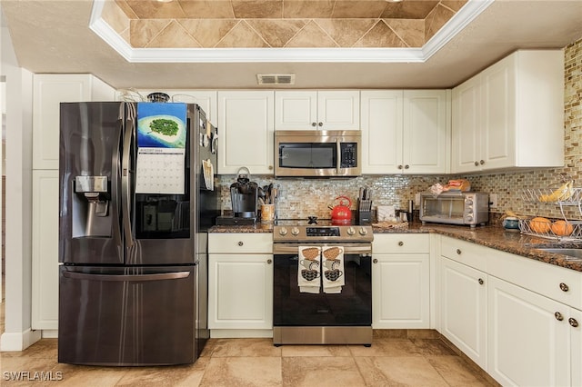 kitchen featuring visible vents, stainless steel appliances, white cabinets, a toaster, and decorative backsplash