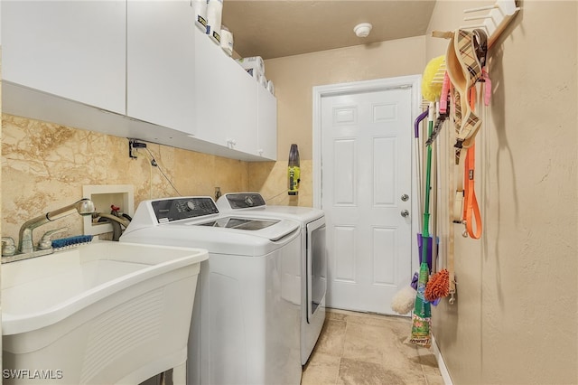 washroom with cabinet space, washer and dryer, and a sink