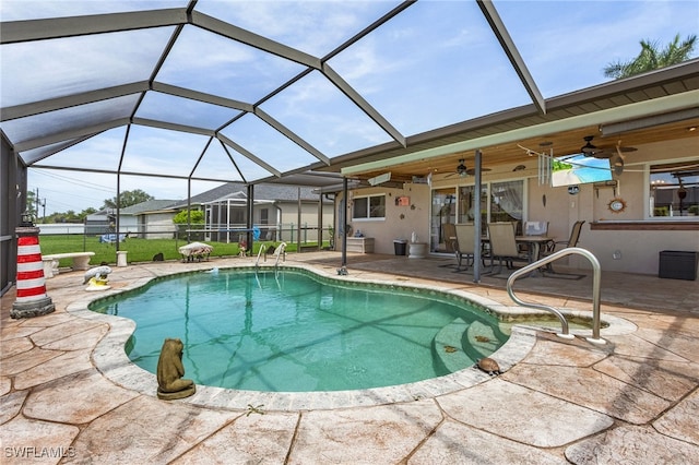 outdoor pool with glass enclosure, fence, ceiling fan, and a patio area