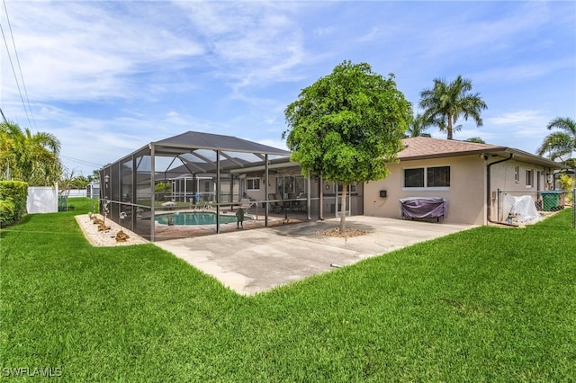 rear view of house with stucco siding, a lawn, fence, glass enclosure, and a patio area