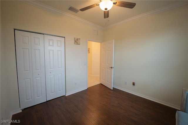 unfurnished bedroom with dark hardwood / wood-style flooring, a closet, ceiling fan, and crown molding