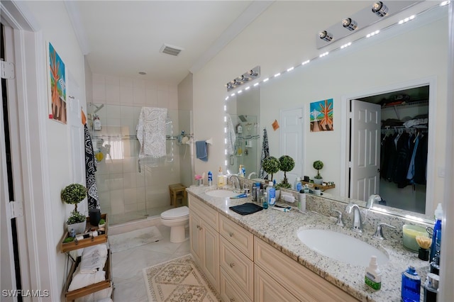 bathroom featuring a shower with door, dual bowl vanity, toilet, tile patterned floors, and ornamental molding