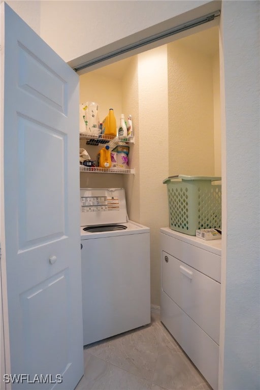 clothes washing area with washer and clothes dryer and light tile patterned floors