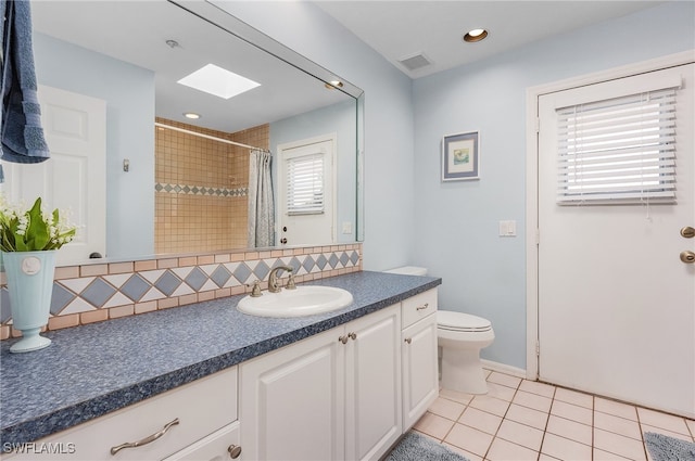 bathroom with a wealth of natural light, tile patterned flooring, vanity, and toilet