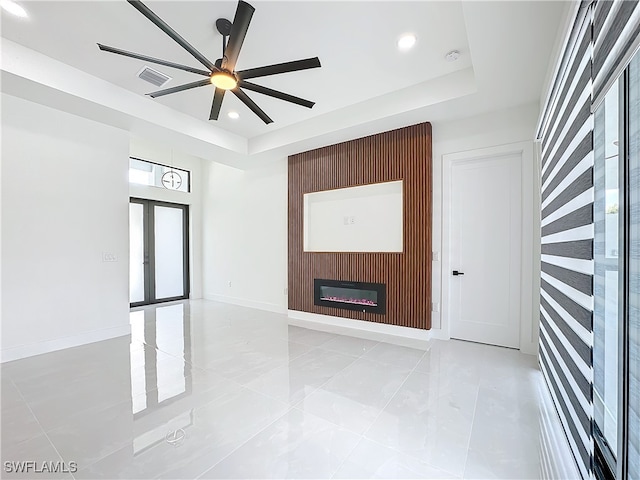 tiled spare room with ceiling fan and a raised ceiling