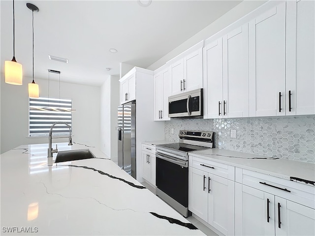 kitchen featuring appliances with stainless steel finishes, backsplash, sink, light stone countertops, and pendant lighting