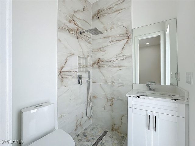 bathroom with toilet, a tile shower, and vanity