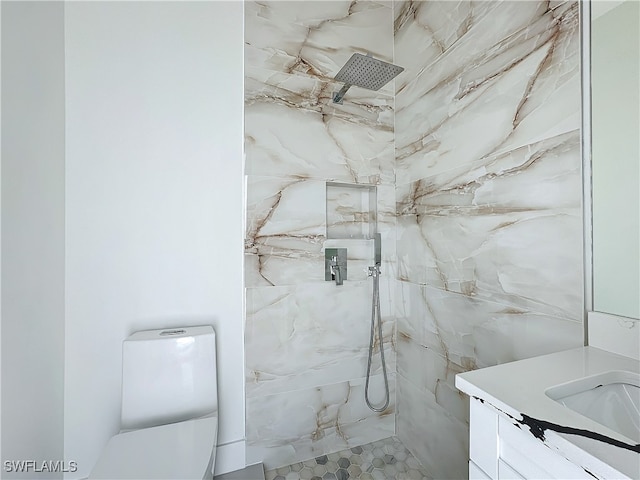 bathroom featuring tiled shower, toilet, and vanity