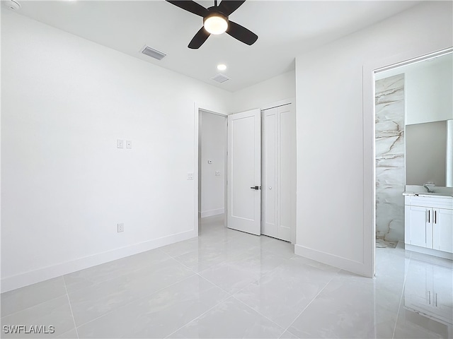 unfurnished bedroom with light tile patterned flooring, a closet, ceiling fan, and ensuite bathroom