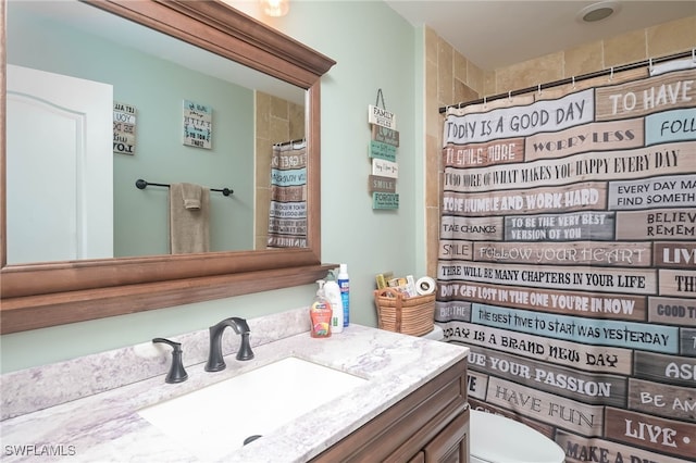 bathroom with walk in shower, vanity, and toilet