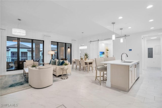 kitchen featuring sink, a kitchen breakfast bar, decorative light fixtures, a barn door, and an island with sink