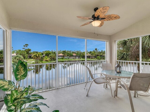 sunroom featuring ceiling fan, a water view, and vaulted ceiling