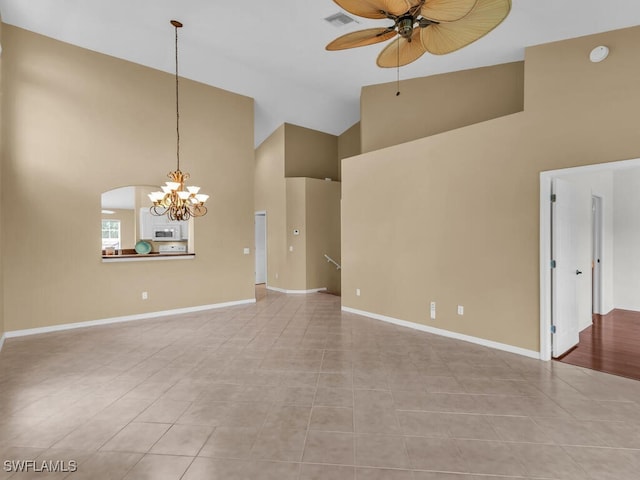 empty room featuring ceiling fan with notable chandelier, light tile patterned floors, and high vaulted ceiling