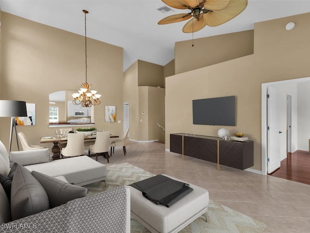 tiled living room featuring ceiling fan with notable chandelier and high vaulted ceiling