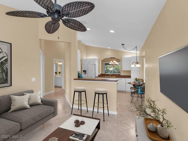 living room with sink, light tile patterned floors, ceiling fan with notable chandelier, and high vaulted ceiling