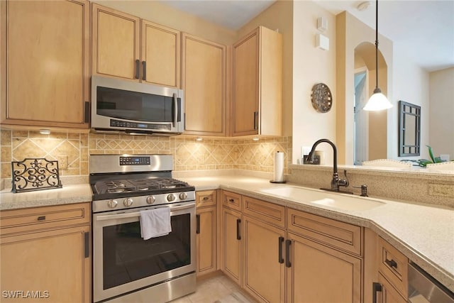 kitchen featuring tasteful backsplash, light tile patterned floors, sink, decorative light fixtures, and stainless steel appliances