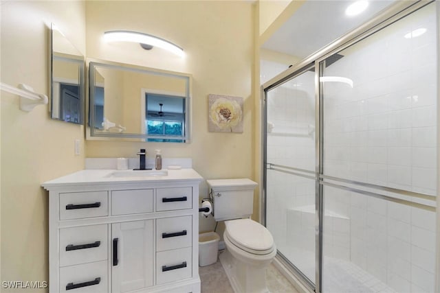 bathroom featuring a shower with door, toilet, vanity, and tile patterned floors