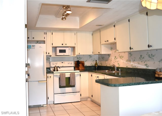 kitchen with a tray ceiling, sink, white cabinets, kitchen peninsula, and white appliances