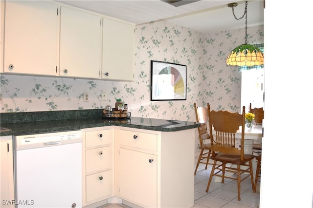 kitchen featuring decorative light fixtures, light tile patterned floors, dishwasher, kitchen peninsula, and dark stone counters