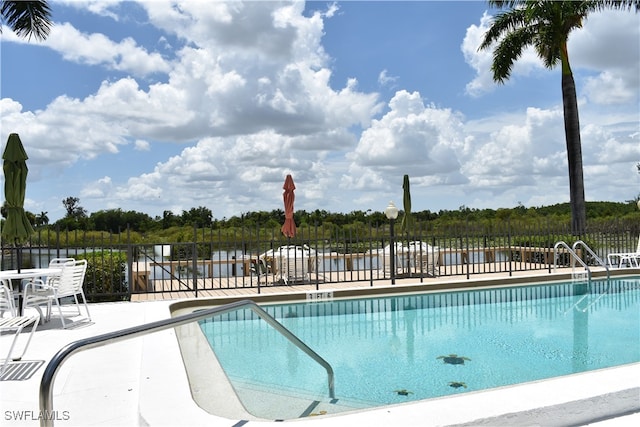 view of pool with a patio and a water view