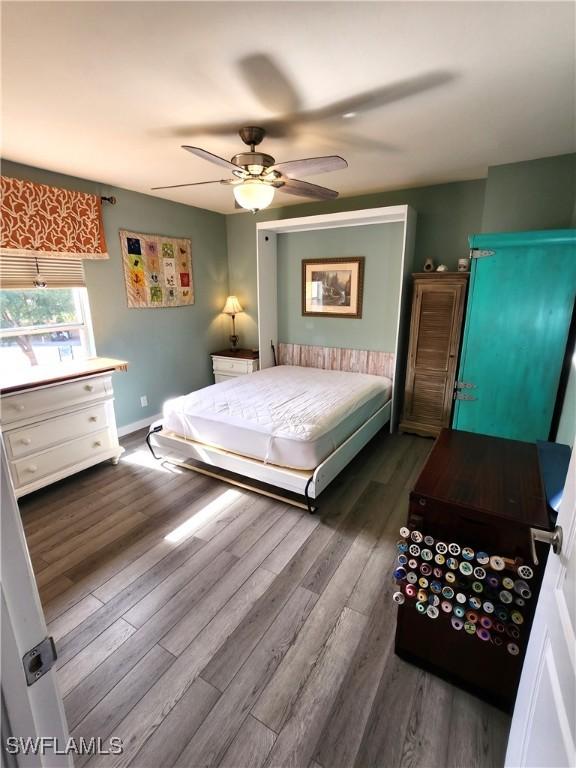 bedroom featuring a ceiling fan, baseboards, and dark wood-style flooring