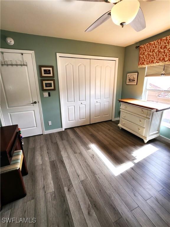 unfurnished bedroom with a ceiling fan, dark wood-style flooring, and baseboards