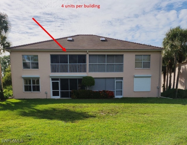 back of house featuring a lawn and stucco siding