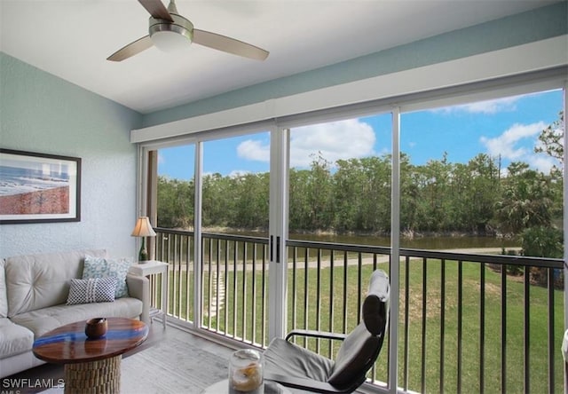 sunroom with a ceiling fan and a water view