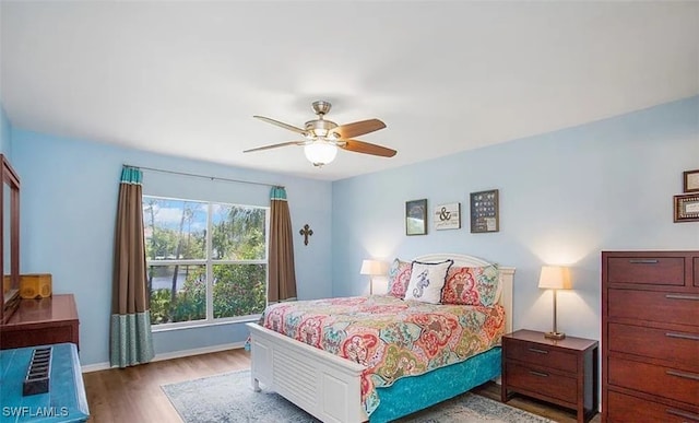 bedroom featuring wood finished floors, a ceiling fan, and baseboards