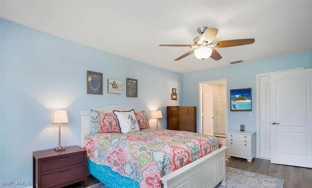 bedroom with dark wood-style floors, visible vents, ceiling fan, and ensuite bath