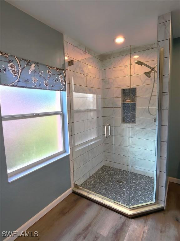 full bathroom with a stall shower, baseboards, and wood finished floors