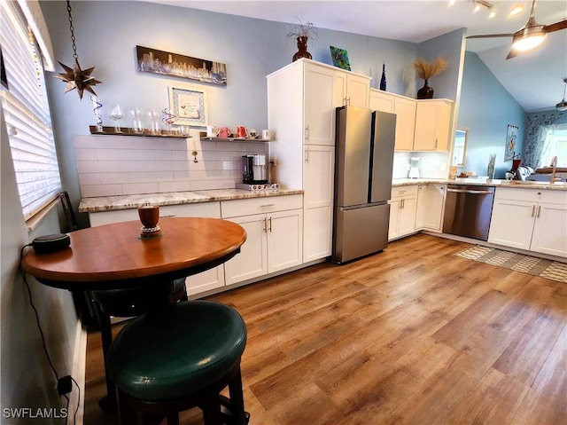 kitchen featuring decorative backsplash, appliances with stainless steel finishes, vaulted ceiling, light wood-type flooring, and open shelves